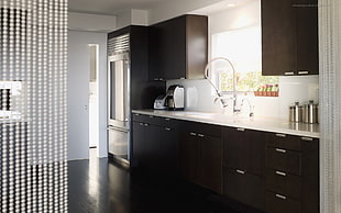 black wooden kitchen cabinet near of gray 3-door refrigerator